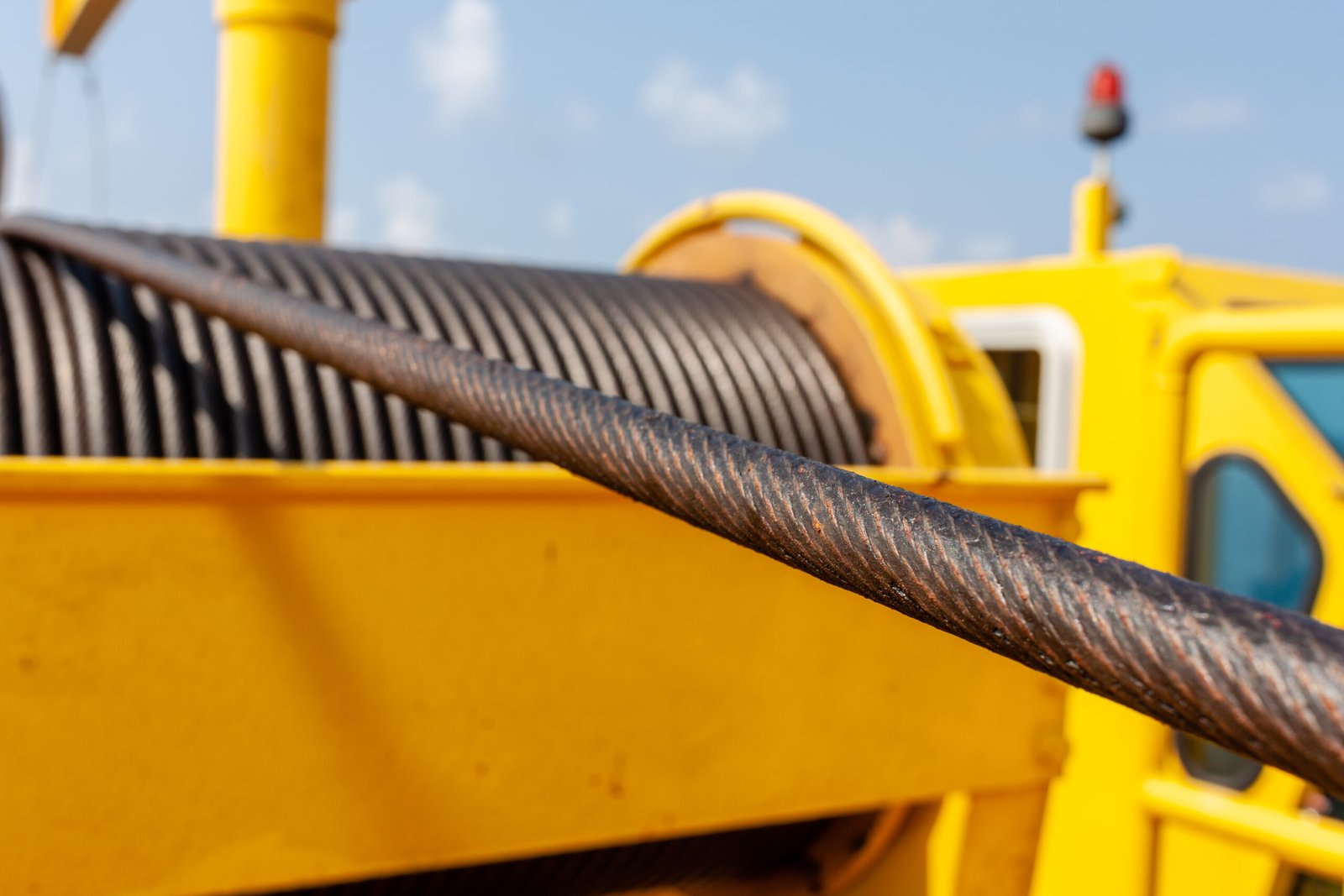 Steel wire rope wound on a yellow industrial winch drum