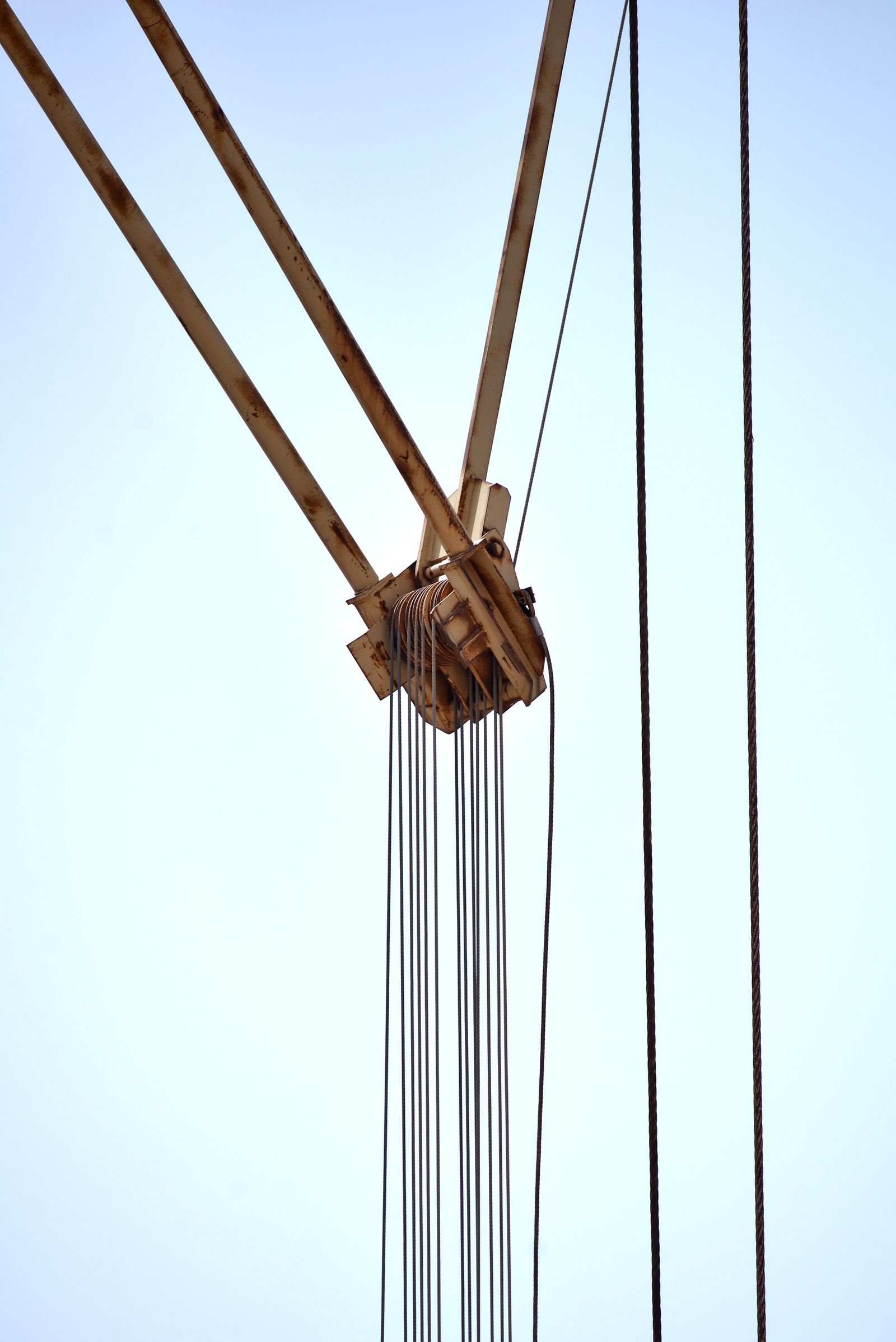 Crane pulley and multiple steel wire ropes against the sky